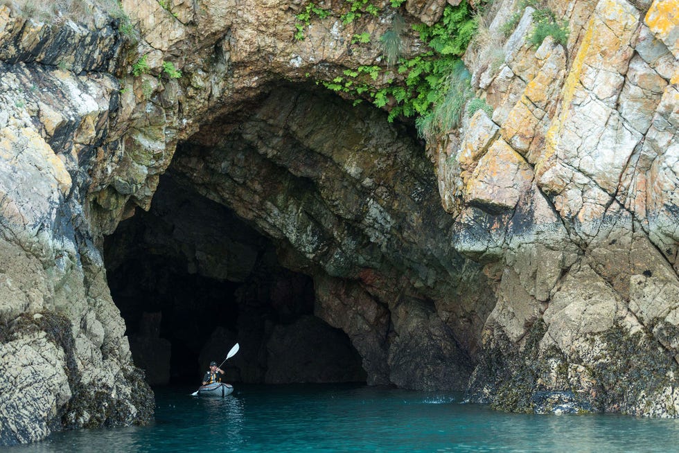 Een kajakker peddelt door een zeegrot op het schiereiland van Crozon in WestFrankrijk