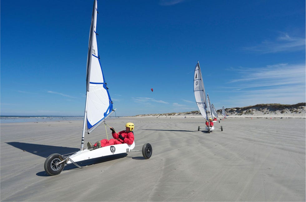 Op hun driewielige voertuigjes scheren zeilwagenrijders over het zand in Bretagne de sport ontstond in Belgi en Frankrijk