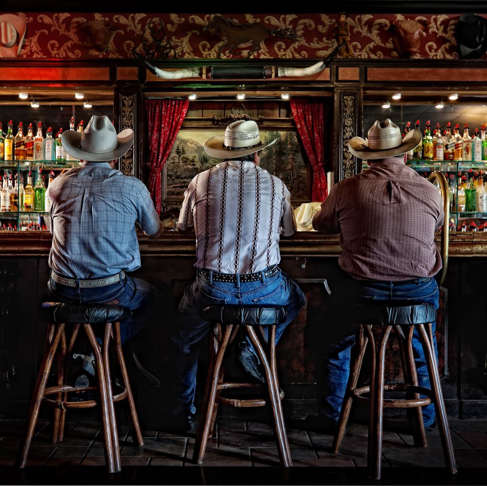 Tres vaqueros se sientan en la barra del River Ranch Saloon