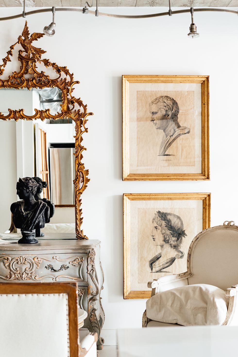 section of a mantle with a mirror on top and a figurine in front of it, surrounded by framed images of pencil sketches