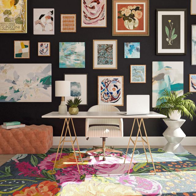 home office with colorful prints on black wall, desk, and chair