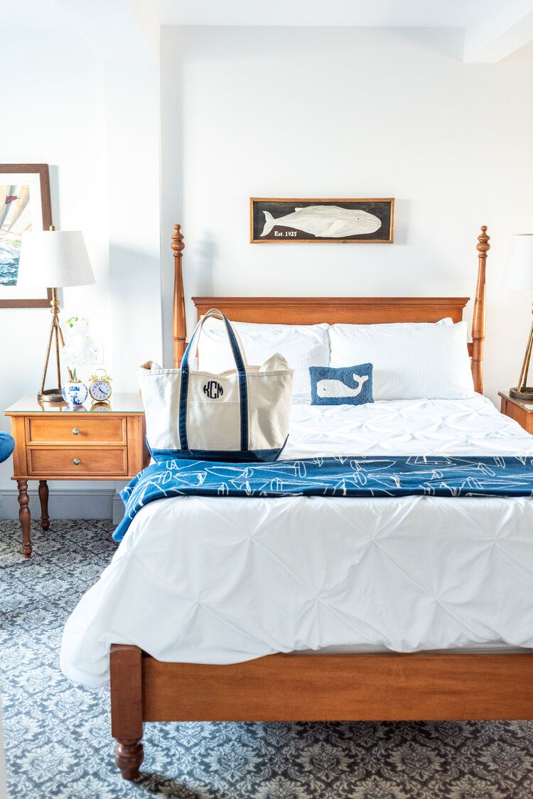 wooden bed with white bedding and small blue whale pillow at the whalers inn