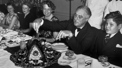 black and white photo of franklin roosevelt carving turkey at thanksgiving dinner