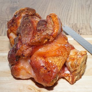 roasted ham hock on a cutting board with a carving knife