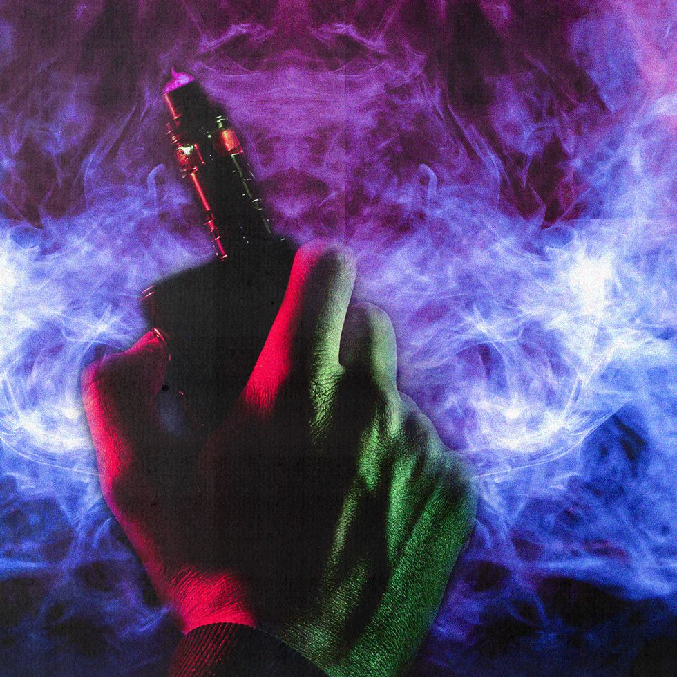 a hand holding a vape with purple smoke surrounding it