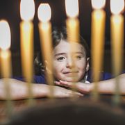 hanukkah meaning  little girl looking at menorah during hanukkah