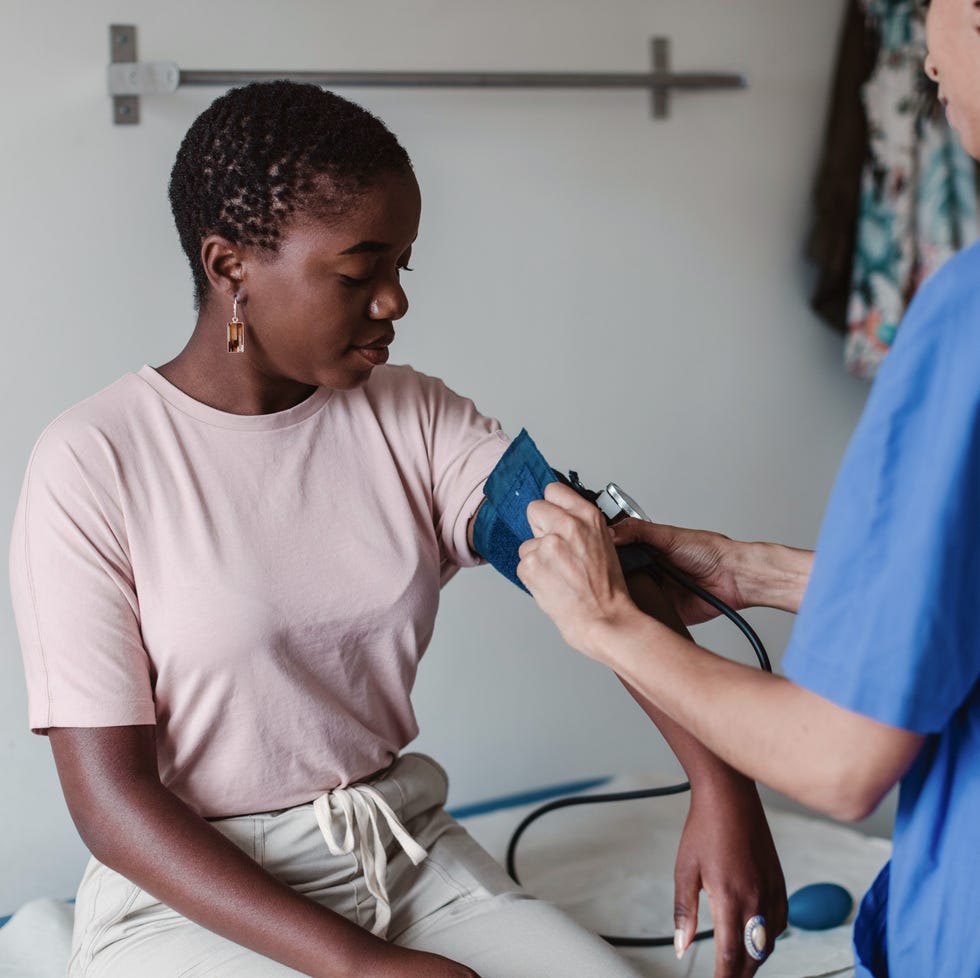 a doctor giving a young woman a blood pressure check up