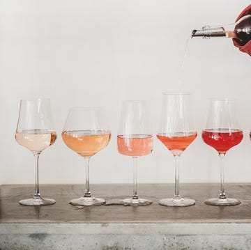 What is rose wine? Different shades of rose wine shades of rose wine in stemmed glasses placed in line from light to deep and womans hand pouring wine from bottle to glass