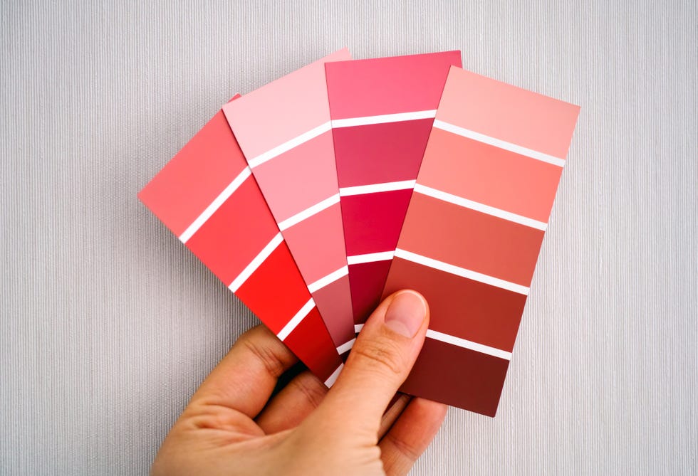 woman hand choosing color in color swatches against wall close up