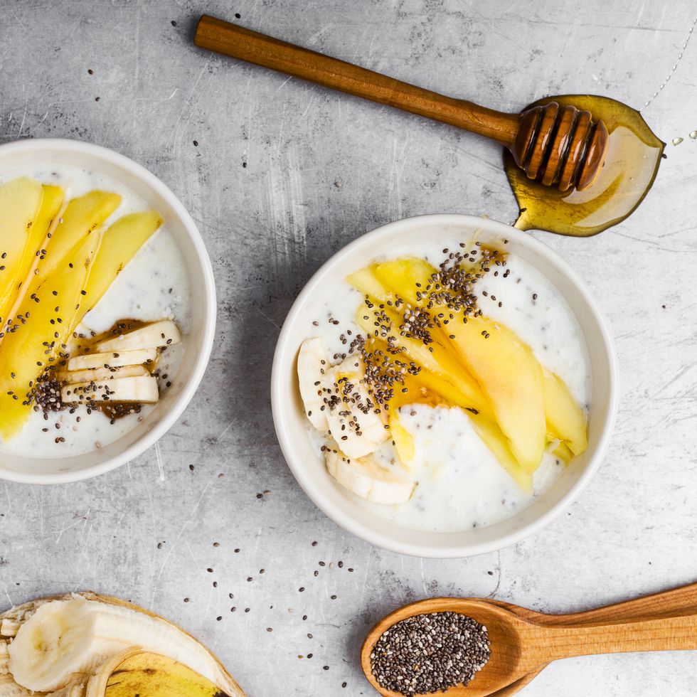 what foods to eat during period for energy mango banana smoothie bowl with natural greek yoghurt and chia seeds, healthy vegetarian dessert with honey on gray rural table viewed from above