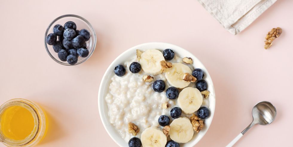 what to eat during periods for energy oatmeal porridge with walnuts, blueberries and banana in bowl on pink   healthy organic breakfast, oats with fruits, honey and nuts