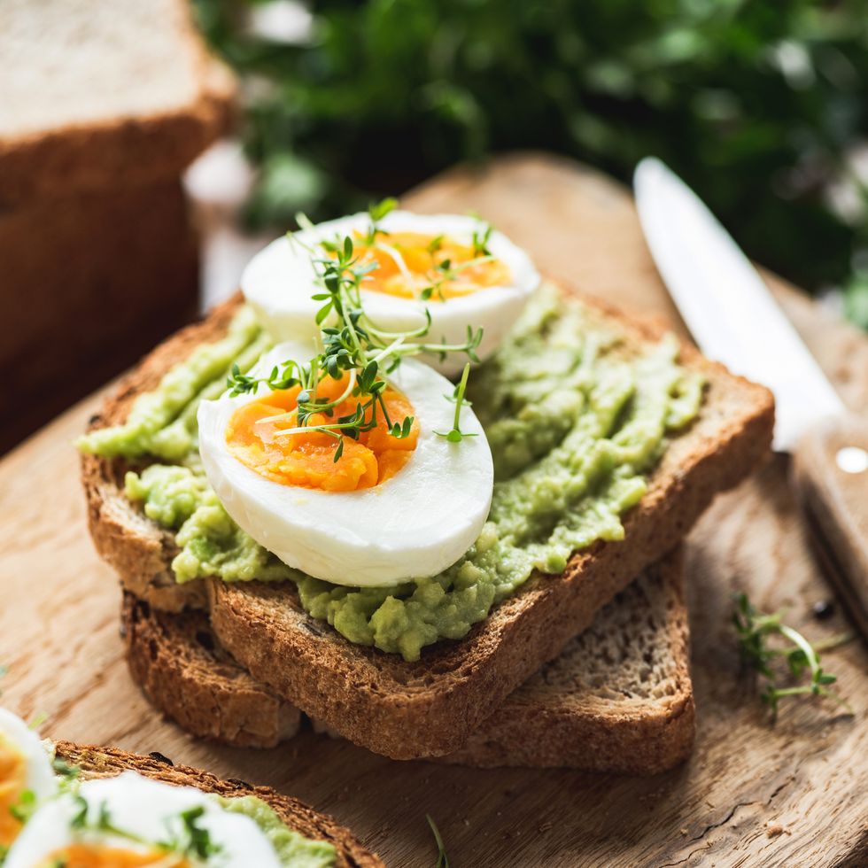 what to eat during your period for entry healhy breakfast toast with avocado, boiled egg on wooden cutting board