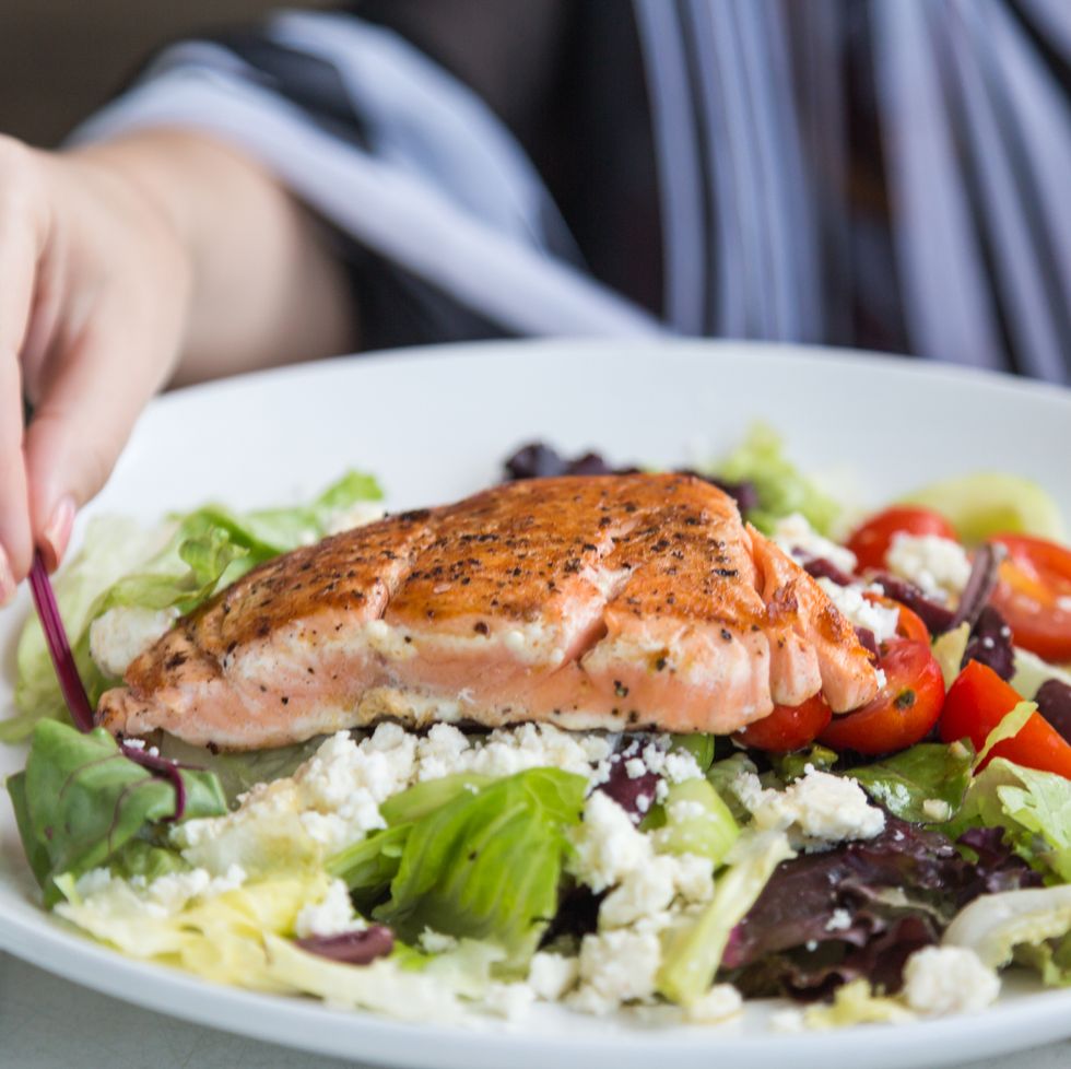 what to eat during your period for energy grilled salmon salad with tomato, feta cheese, lettuce and so on and hand approaching