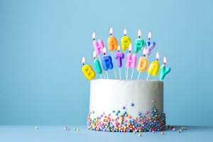 colorful birthday cake with candles spelling happy birthday set against a blue background