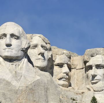 a group of statues of men with mount rushmore national memorial in the background