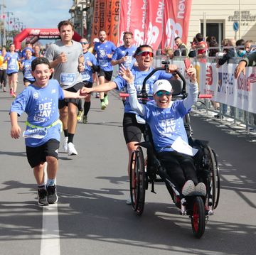 a group of people running on a street with a person on a wheelchair