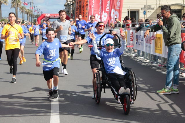a group of people running on a street with a person on a wheelchair