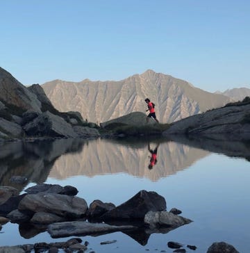 a person running alongside a serene mountain lake