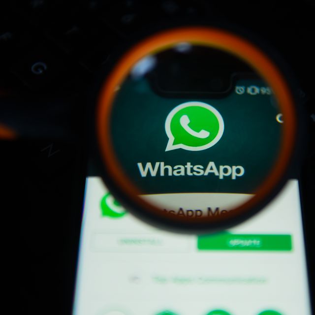 WhatsApp logo is seen trough a magnifying glass on an...
