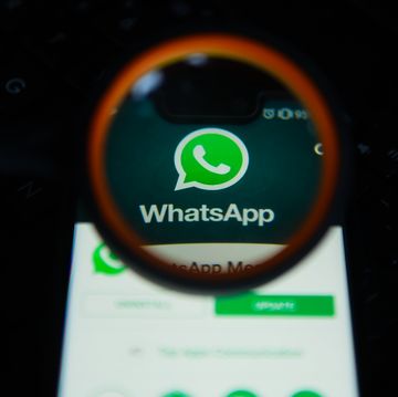 WhatsApp logo is seen trough a magnifying glass on an...