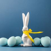 several blue dyed easter eggs and white easter bunny with yellow ribbon bow on table holiday eggs hunt and painting concept