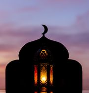 when is eid al fitr 2023 lantern with blurred focus of mosque background that has moon symbol on top and dawn sky