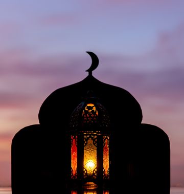 when is eid al fitr 2023 lantern with blurred focus of mosque background that has moon symbol on top and dawn sky