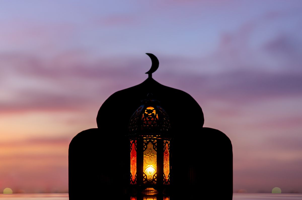 when is eid al fitr 2022 lantern with blurred focus of mosque background that has moon symbol on top and dawn sky