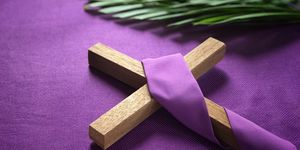 a religious cross and palm leaves on purple background