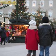 young boy and girl, siblings, are walking hand in hand towards the christmas market