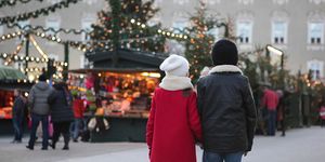 young boy and girl, siblings, are walking hand in hand towards the christmas market
