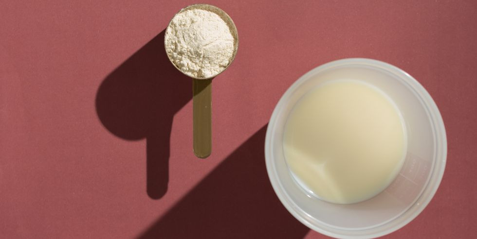 whey protein minimalism concept and hard light scoop with vanilla powder and glass of milk on brown background