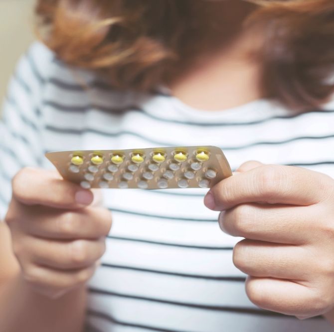 which pill is right for me woman hands opening birth control pills in hand on the bed in the bedroom eating contraceptive pill