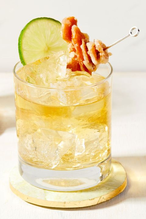 glass of whiskey ginger cocktail garnished with candied ginger and a lime wheel
