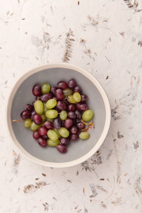 White and crimson grapes in grey bowl.
