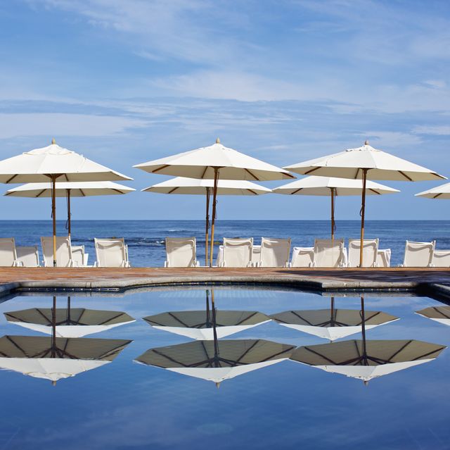 white beach umbrellas and lounge chairs at sunny ocean poolside, punta de mita, nayarit, mexico