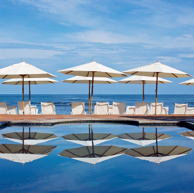 white beach umbrellas and lounge chairs at sunny ocean poolside, punta de mita, nayarit, mexico