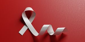 White Blindeness And Bone Cancer Awareness Ribbon On Red Background
