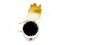 a white ceramic cup of black espresso coffee and light bubble with brown stained of coffee water spotted on white backgrounds and copy space, top view angle of shooting image