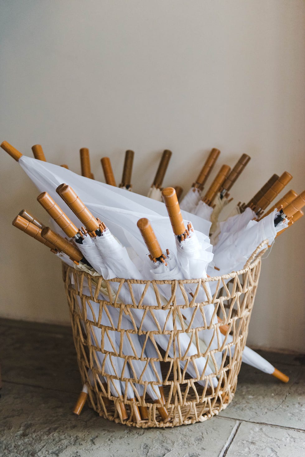 white closed folding umbrellas with wooden handles stand in a basket outdoors in summer