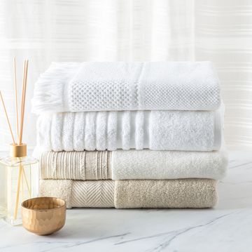 white cotton bath towels folded and aroma diffuser on a white marble table in the bathroom neutral color, close up