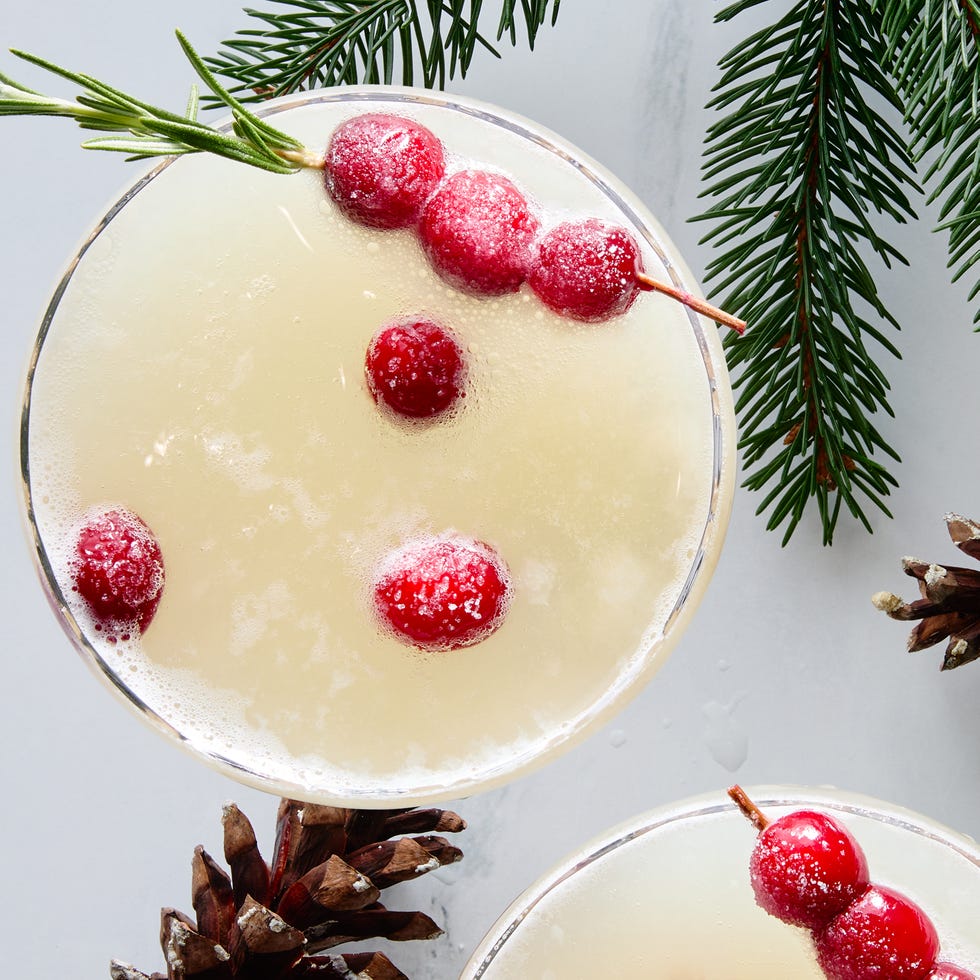 white cocktail garnished with sugared cranberries and rosemary