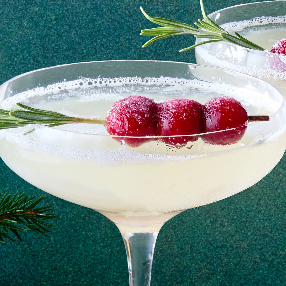 white cocktail garnished with sugared cranberries and rosemary