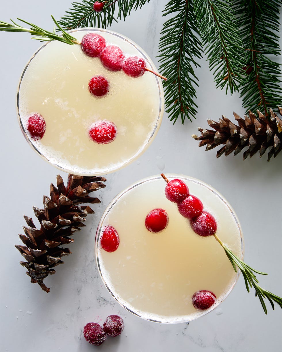 white cocktail garnished with sugared cranberries and rosemary