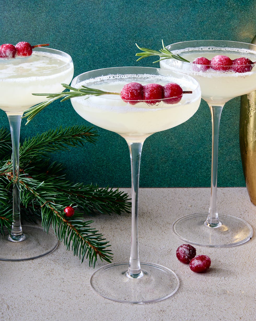 white cocktail garnished with sugared cranberries and rosemary