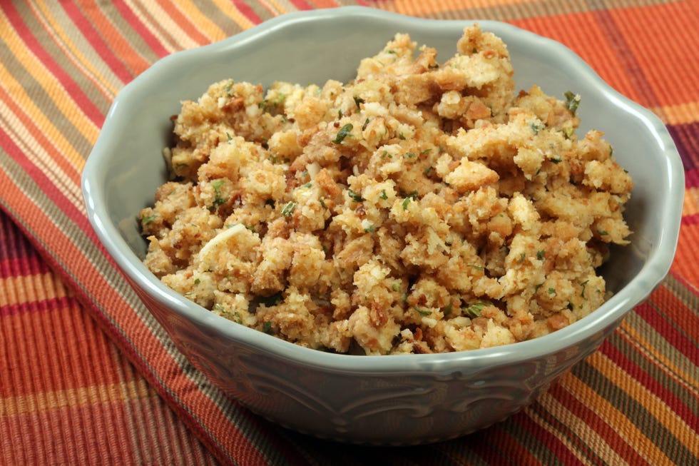 white decorative bowl of stuffing on a striped tablecloth