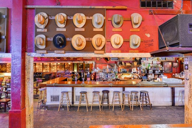 a bar with stools and a large sign