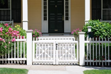 White fence with gate over a garden and a house's front door