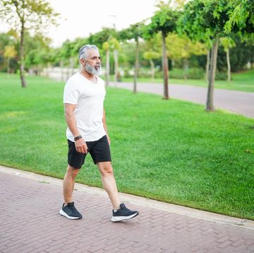 white haired and bearded man walking in the park