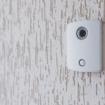 a white incoming electronic doorbell with a camera on the wall of the building, office